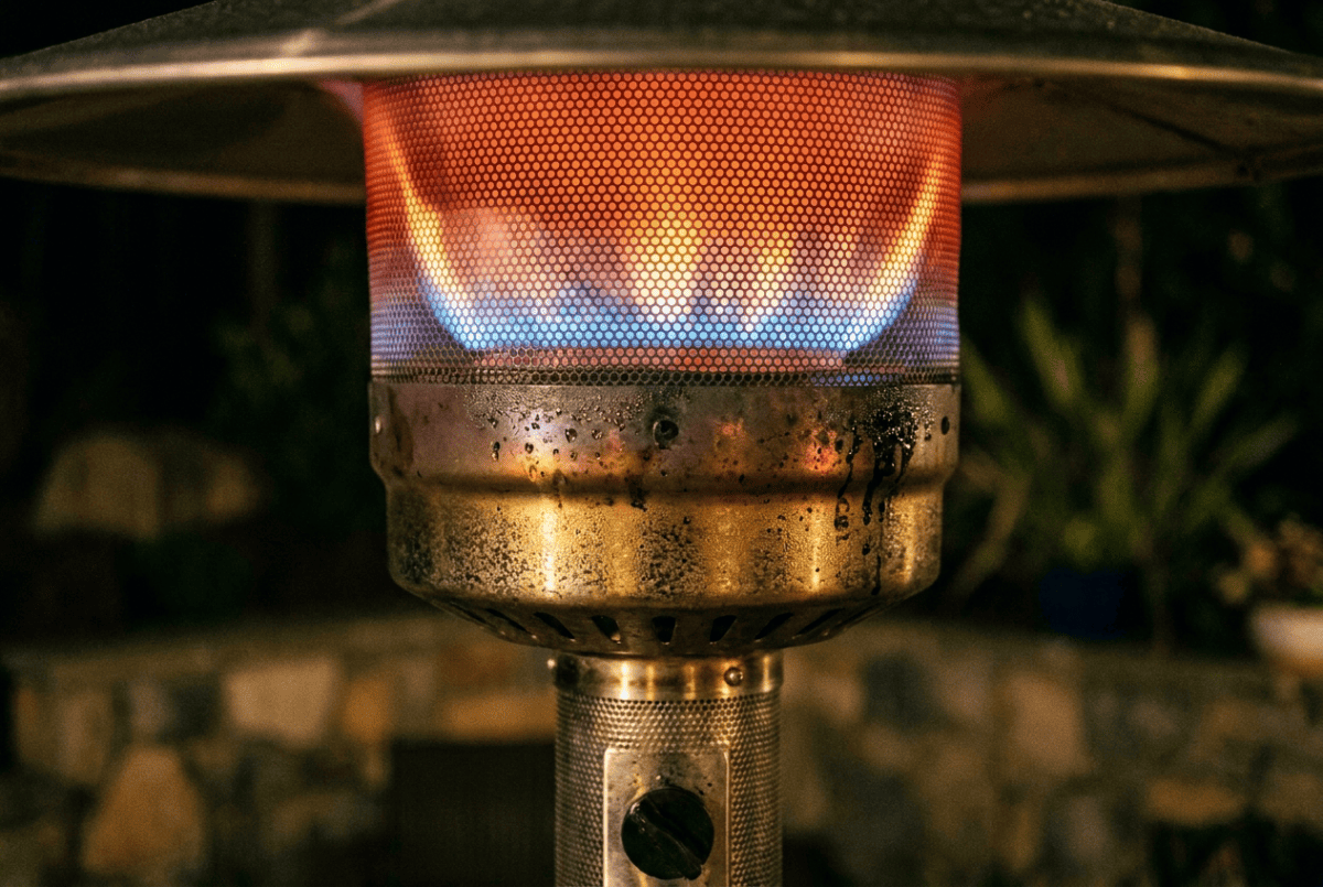 Close-up of a propane patio heater burner flame under the mesh screen